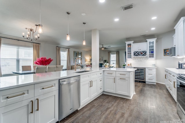 kitchen with stainless steel appliances, white cabinets, beverage cooler, and kitchen peninsula