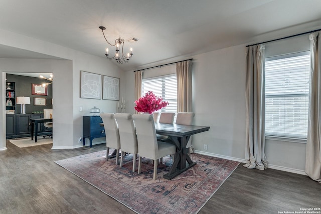 dining space with an inviting chandelier, vaulted ceiling, and dark wood-type flooring