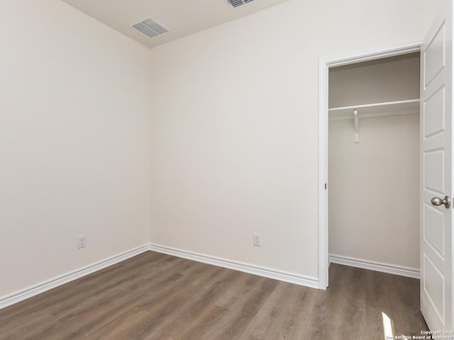 unfurnished bedroom featuring a closet, wood finished floors, visible vents, and baseboards