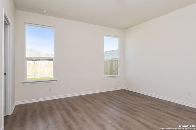 spare room featuring baseboards and wood finished floors