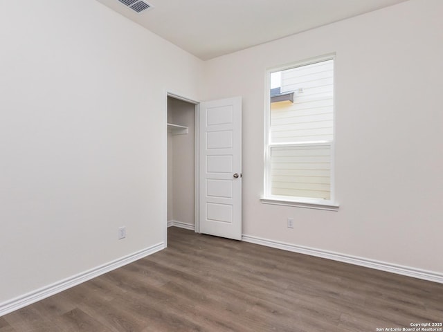 unfurnished bedroom with wood finished floors, visible vents, and baseboards