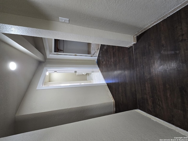 hall with a textured ceiling and wood walls