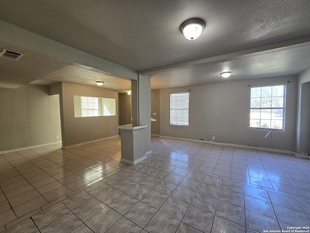 tiled empty room featuring a textured ceiling and a healthy amount of sunlight