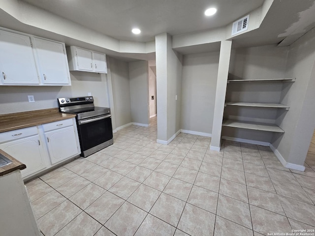 kitchen with white cabinetry, stainless steel electric stove, light tile patterned floors, and built in features