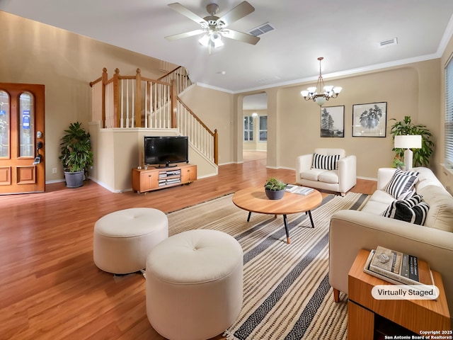 living room featuring crown molding, wood-type flooring, and ceiling fan with notable chandelier