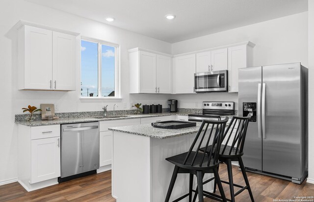 11707 Anselmo, San Antonio, TX 78254 - kitchen with sink, dark wood-type flooring, stainless steel appliances, light stone counters, and white cabinets