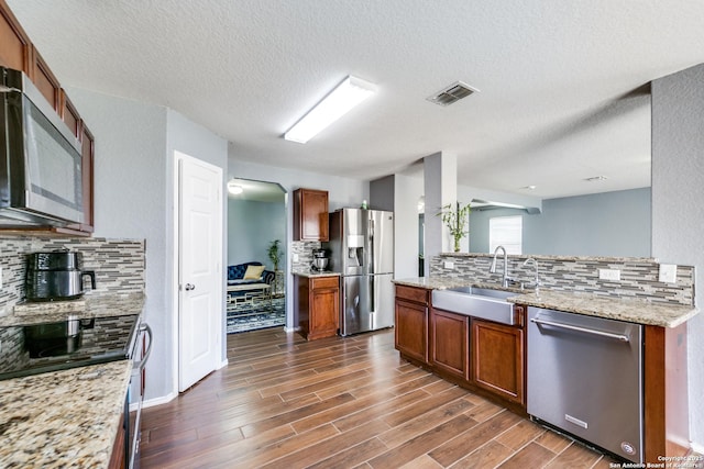 kitchen featuring light stone counters, sink, backsplash, and appliances with stainless steel finishes