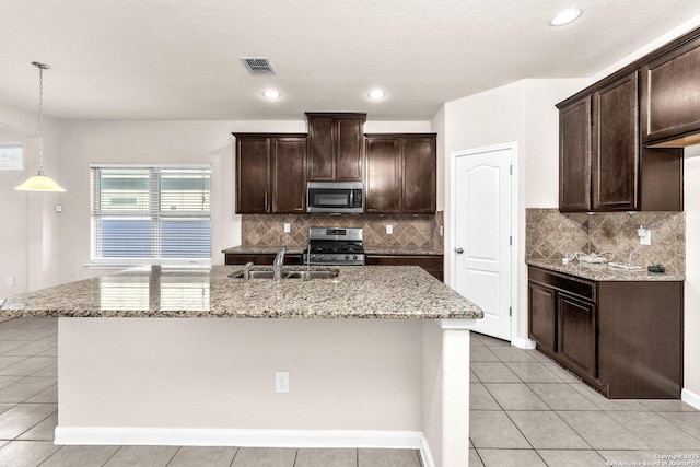 kitchen featuring dark brown cabinetry, appliances with stainless steel finishes, sink, and a center island with sink