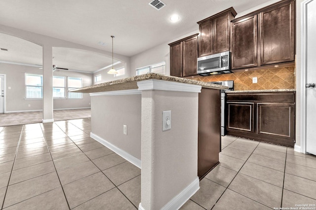 kitchen featuring appliances with stainless steel finishes, light tile patterned floors, dark brown cabinets, and plenty of natural light