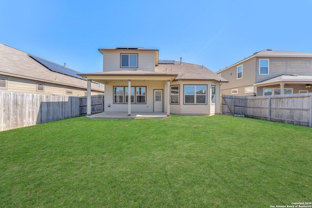 rear view of property with a lawn, a patio, and solar panels