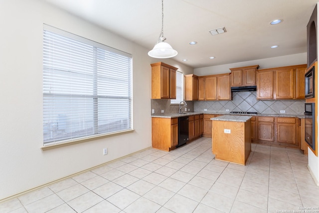 kitchen with tasteful backsplash, hanging light fixtures, a center island, light stone counters, and black appliances