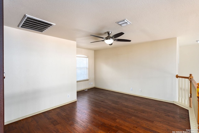 spare room featuring dark wood-type flooring, ceiling fan, and a textured ceiling