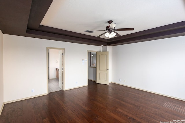 unfurnished bedroom featuring connected bathroom, a tray ceiling, ceiling fan, and hardwood / wood-style flooring