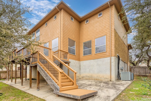 rear view of property featuring central AC unit, a deck, and a patio