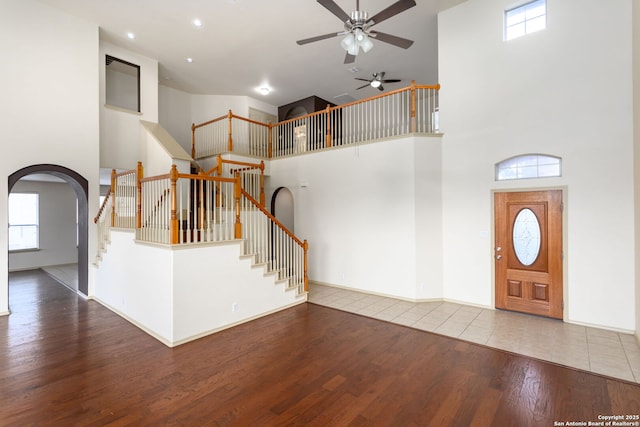 foyer featuring ceiling fan, a healthy amount of sunlight, hardwood / wood-style floors, and a high ceiling