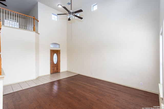 foyer featuring a towering ceiling, light hardwood / wood-style flooring, and ceiling fan