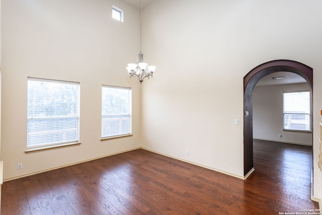 unfurnished room featuring dark hardwood / wood-style floors, a chandelier, and a high ceiling