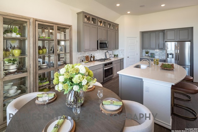 kitchen featuring stainless steel appliances, tasteful backsplash, sink, and a center island with sink