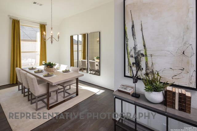 dining space with dark hardwood / wood-style flooring, plenty of natural light, and an inviting chandelier