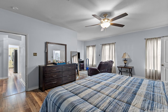 bedroom featuring wood-type flooring, stainless steel fridge, and ceiling fan