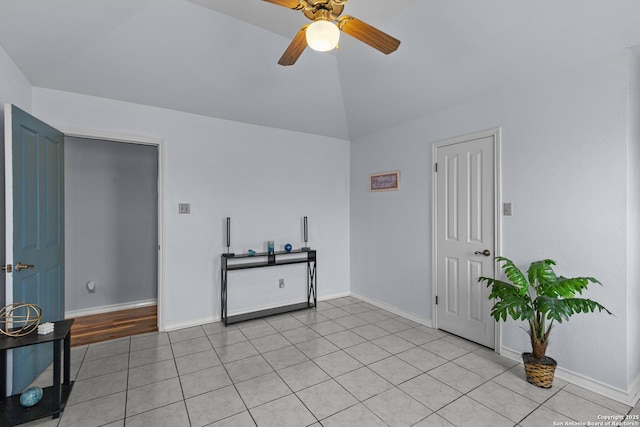 empty room with lofted ceiling, light tile patterned floors, and ceiling fan