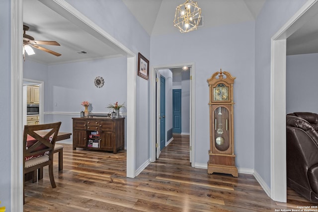 hallway featuring crown molding, dark hardwood / wood-style flooring, a chandelier, and vaulted ceiling