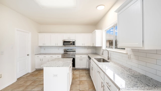 kitchen with white cabinetry, sink, a center island, light stone counters, and stainless steel appliances