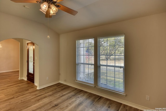 empty room featuring ceiling fan, vaulted ceiling, and wood-type flooring