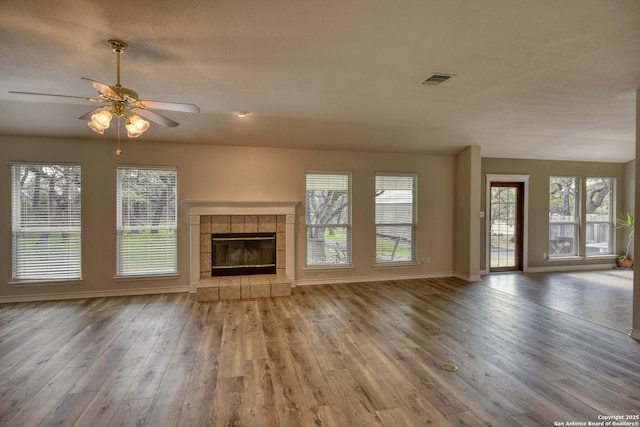 unfurnished living room with ceiling fan, light hardwood / wood-style floors, and a tile fireplace