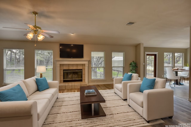 living room featuring ceiling fan, a fireplace, and light hardwood / wood-style flooring