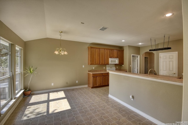 kitchen with pendant lighting, sink, lofted ceiling, and an inviting chandelier