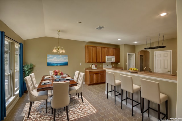 dining room with vaulted ceiling, sink, and a notable chandelier