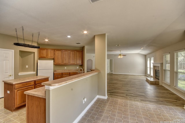 kitchen with lofted ceiling, ceiling fan, a center island, kitchen peninsula, and white fridge