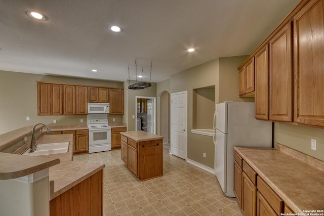 kitchen with white appliances, sink, a kitchen island, and a textured ceiling