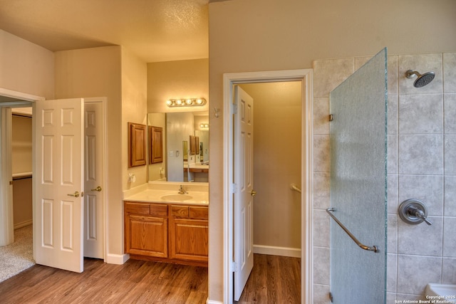 bathroom featuring hardwood / wood-style floors, tiled shower, and vanity