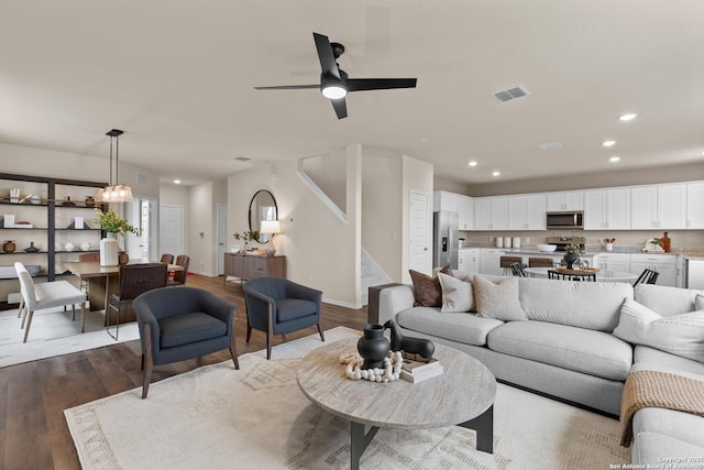 living room featuring ceiling fan with notable chandelier and light hardwood / wood-style floors