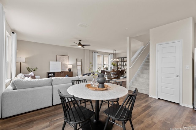 dining room with dark wood-type flooring and ceiling fan with notable chandelier