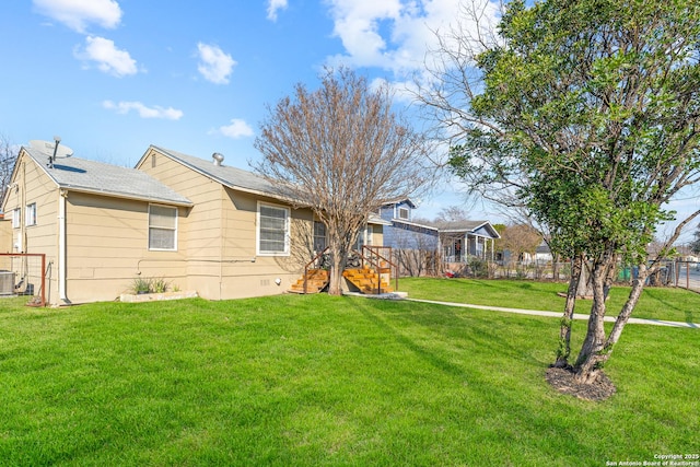 rear view of house featuring central AC unit and a lawn