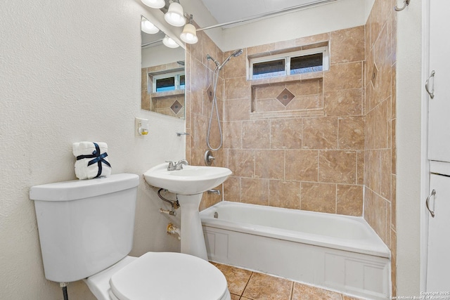 bathroom featuring toilet, tiled shower / bath combo, and tile patterned flooring