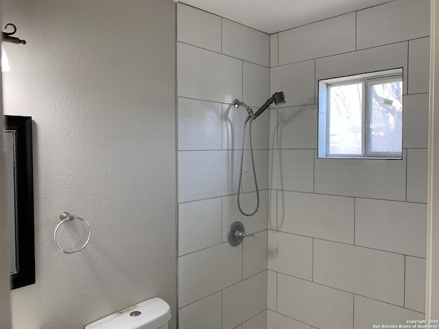 bathroom featuring toilet and a tile shower