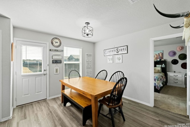 dining area with wood-type flooring and a textured ceiling