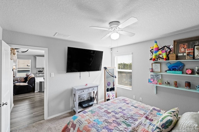 carpeted bedroom featuring ceiling fan and a textured ceiling