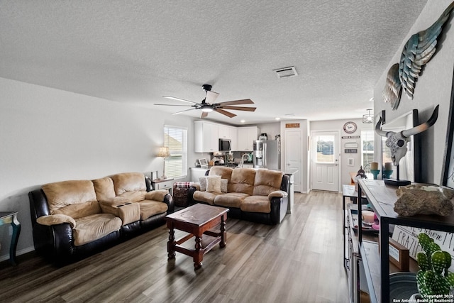 living room featuring hardwood / wood-style flooring, ceiling fan, and a textured ceiling