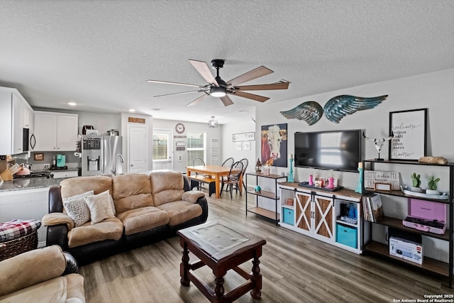 living room with hardwood / wood-style floors, a textured ceiling, and ceiling fan