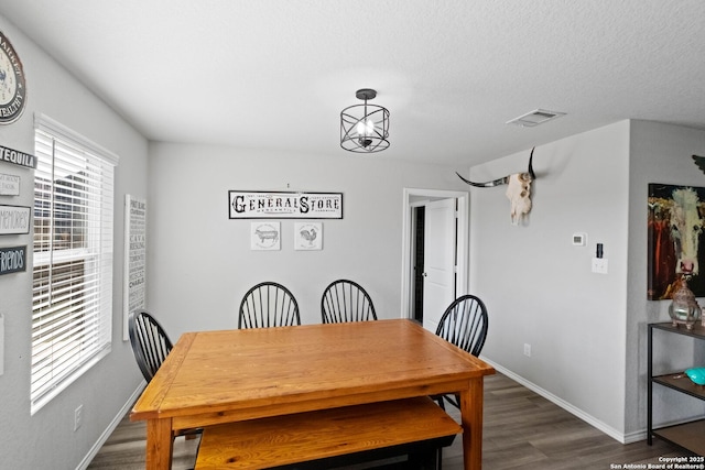 dining space featuring dark wood-type flooring and a textured ceiling