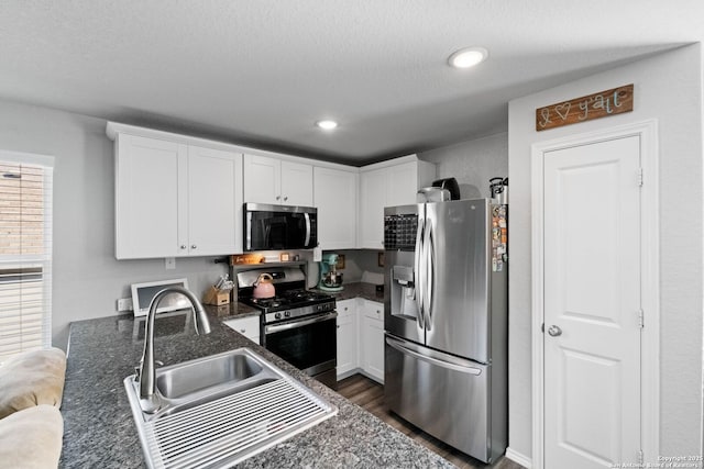 kitchen with sink, dark hardwood / wood-style flooring, kitchen peninsula, stainless steel appliances, and white cabinets