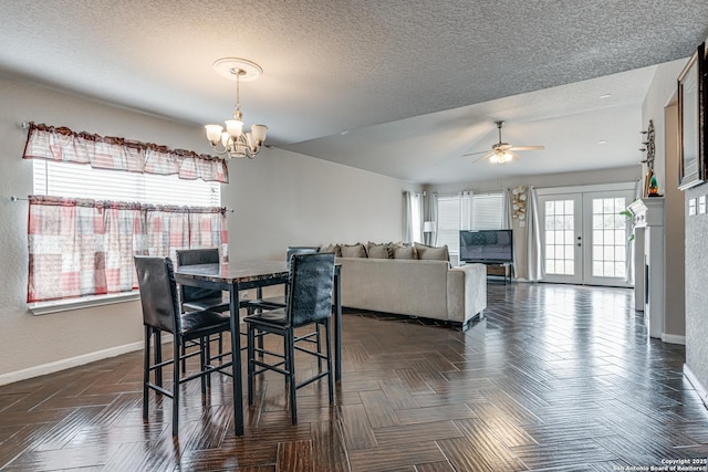 dining room with dark parquet flooring, ceiling fan with notable chandelier, french doors, and a textured ceiling