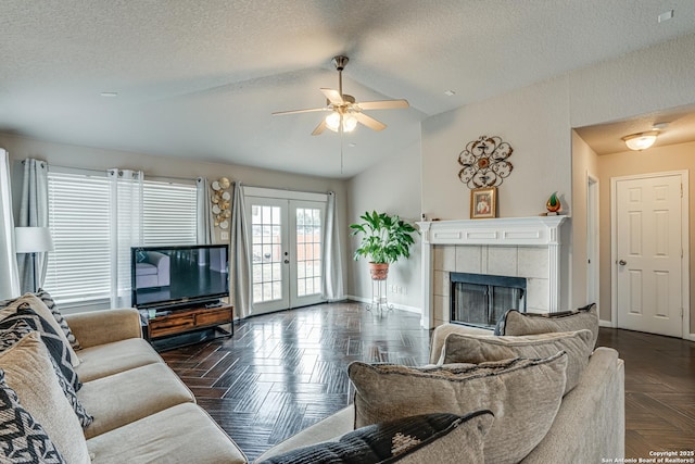 living room with french doors, vaulted ceiling, a textured ceiling, dark parquet floors, and a fireplace