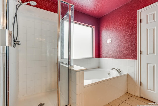 bathroom with tile patterned flooring, a textured ceiling, and separate shower and tub