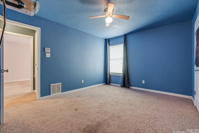 empty room with ceiling fan, carpet, and a textured ceiling